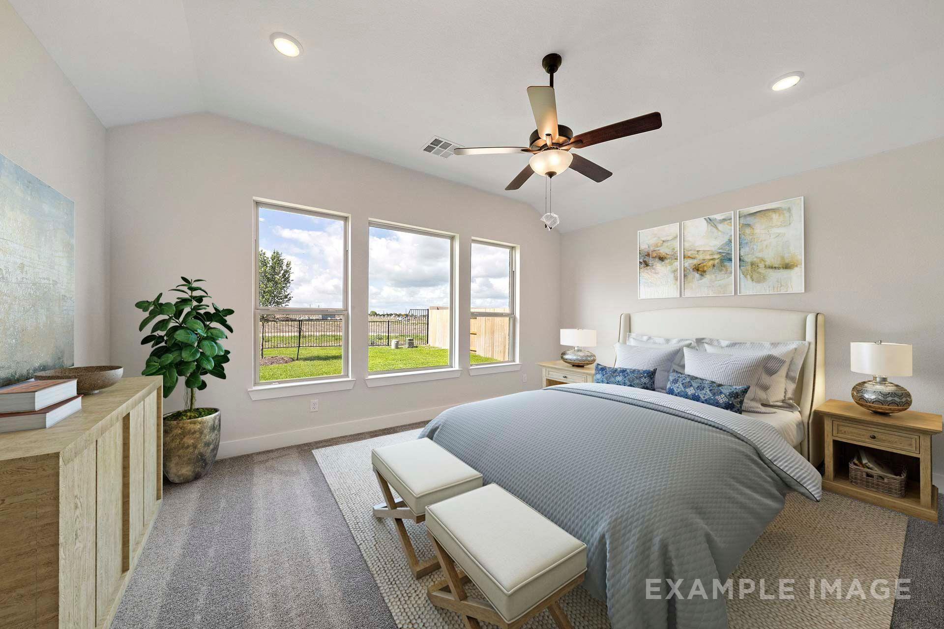 Bright master suite in The Victoria by Davidson Homes with king bed, vaulted ceiling, ceiling fan, and backyard-facing windows in Texas City.