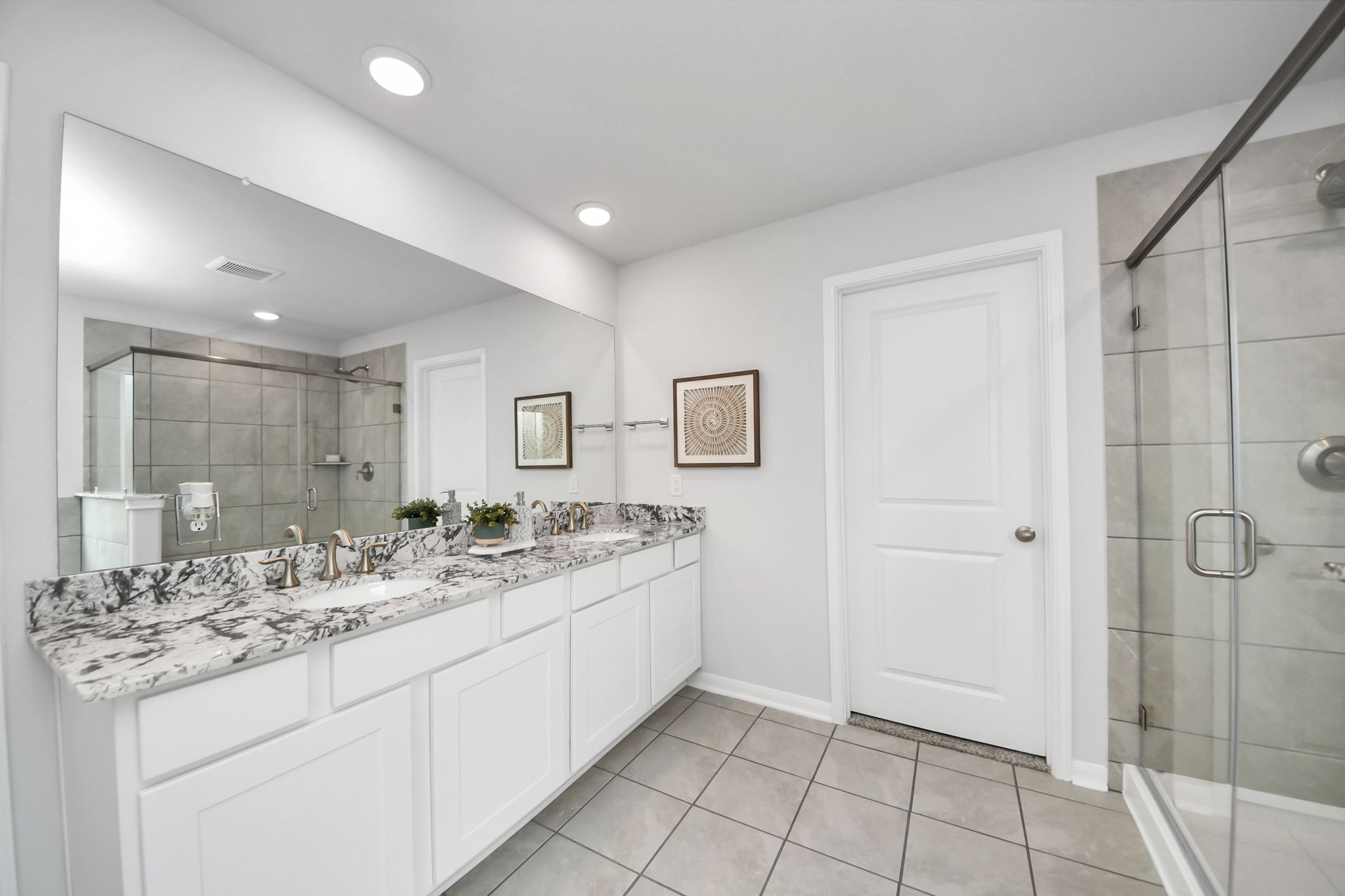 Modern primary bathroom at Sunterra in Katy, TX by Davidson Homes featuring dual vanity and glass-enclosed shower.