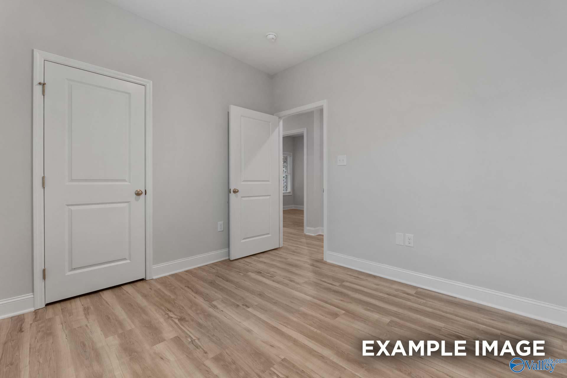 Spacious bedroom hallway with white doors, gray walls, and laminate wood flooring in Davidson Homes Cumberland B, Decatur AL