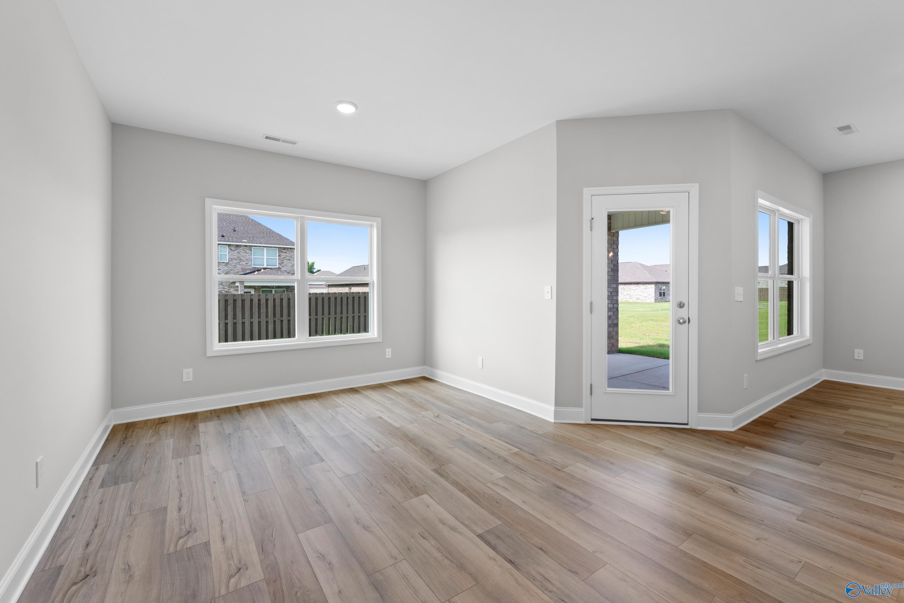 Spacious living room with hardwood floors, large windows, and sliding glass door to backyard in Davidson Homes The Everett B, Toney, Alabama