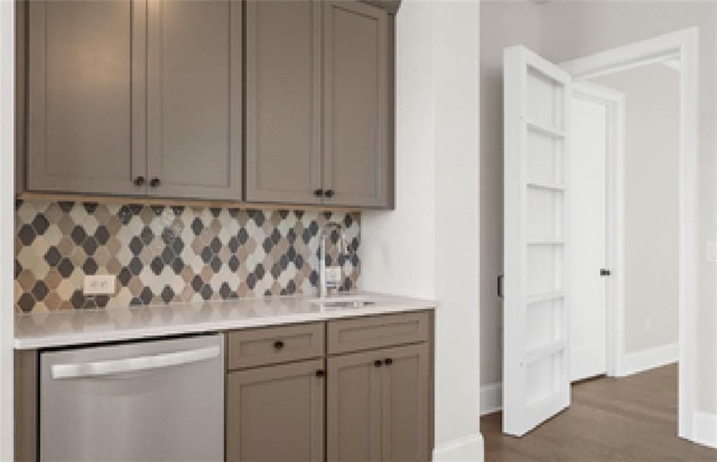 Spacious butler's pantry with taupe shaker cabinets, geometric mosaic backsplash, stainless sink in Davidson Homes The Seaside A, Woodstock, GA