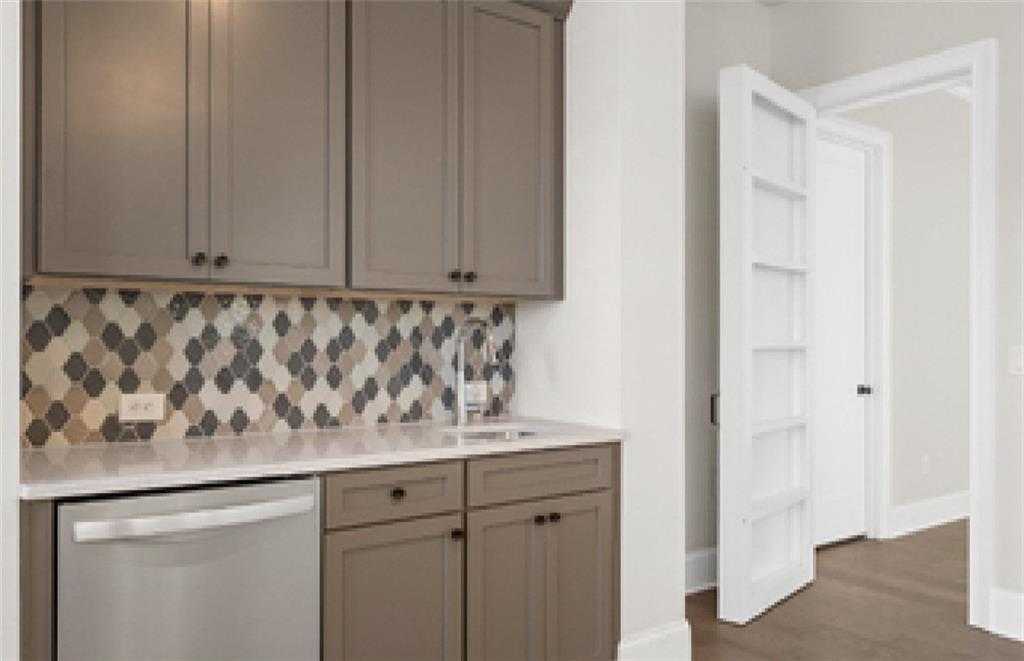 Spacious butler's pantry with taupe shaker cabinets, geometric mosaic backsplash, stainless sink in Davidson Homes The Seaside A, Woodstock, GA