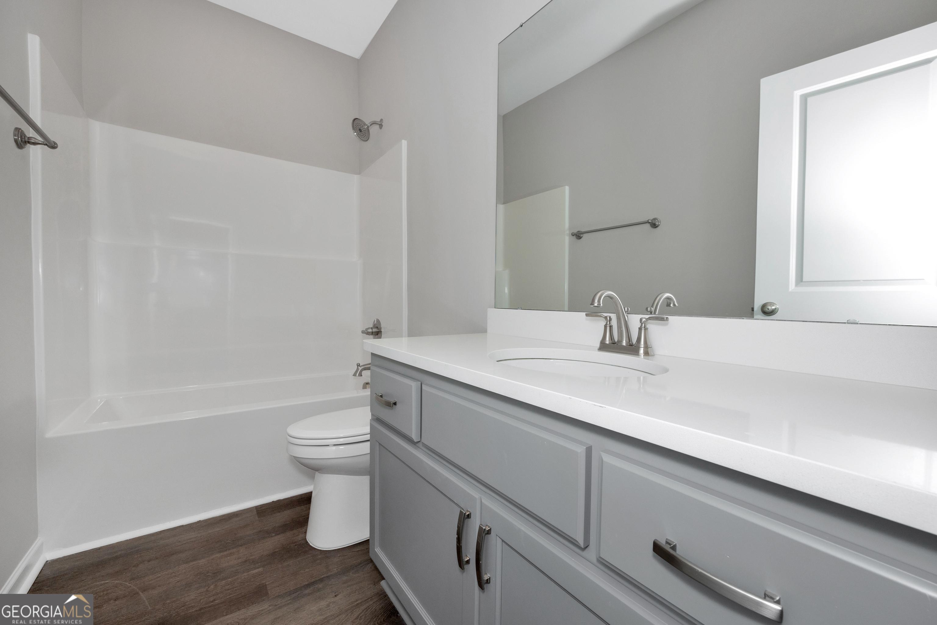 Modern bathroom with gray shaker vanity, white quartz countertop, tub-shower combo in Evermore Homes The Luna, Perry, Georgia
