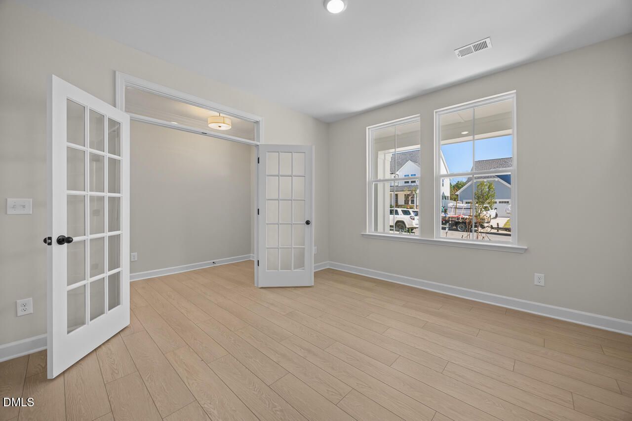 Bright flexible room with French doors and hardwood-style flooring in Davidson Homes The Ashport M plan at Wendell Ridge, NC