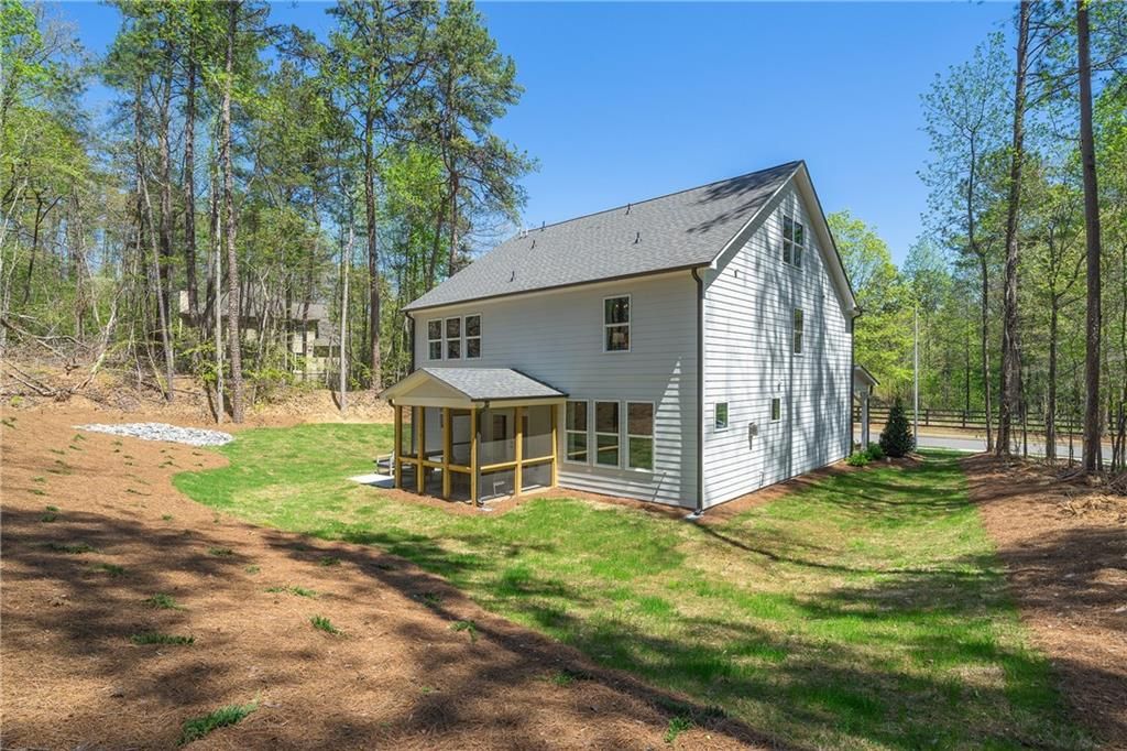 Two-story white home exterior with covered porch, gabled roof, and wooded backyard in Riverwood, Dallas, Georgia by Davidson Homes