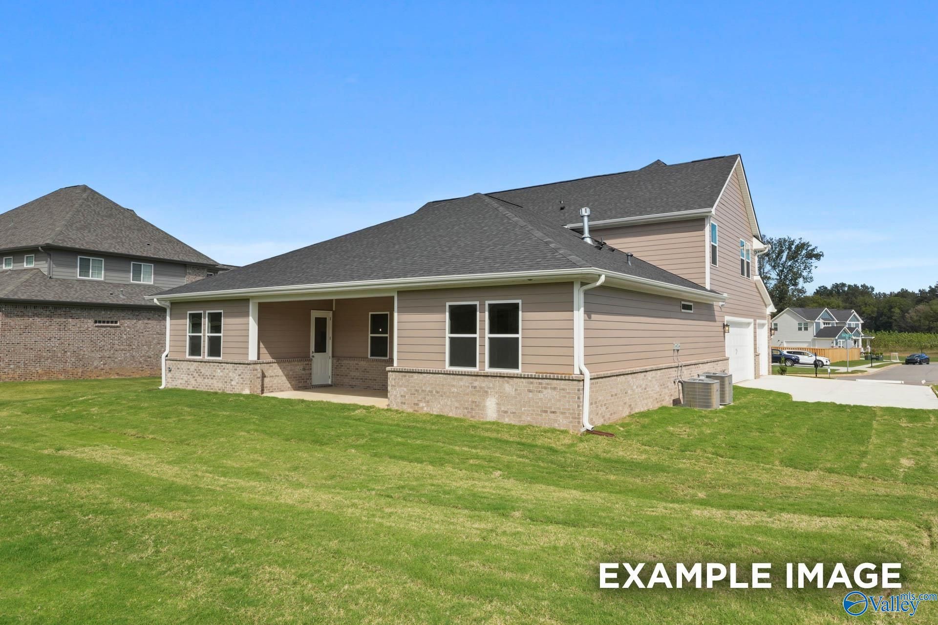 Two-story beige-sided home with dark shingle roof, 2-car garage, covered porch, and lush green lawn in The Meadows at Hampton Cove, Owens Cross Roads, AL