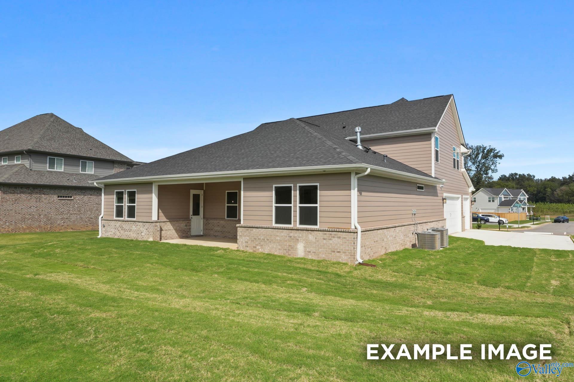 Two-story beige-sided home with dark shingle roof, 2-car garage, covered porch, and lush green lawn in The Meadows at Hampton Cove, Owens Cross Roads, AL