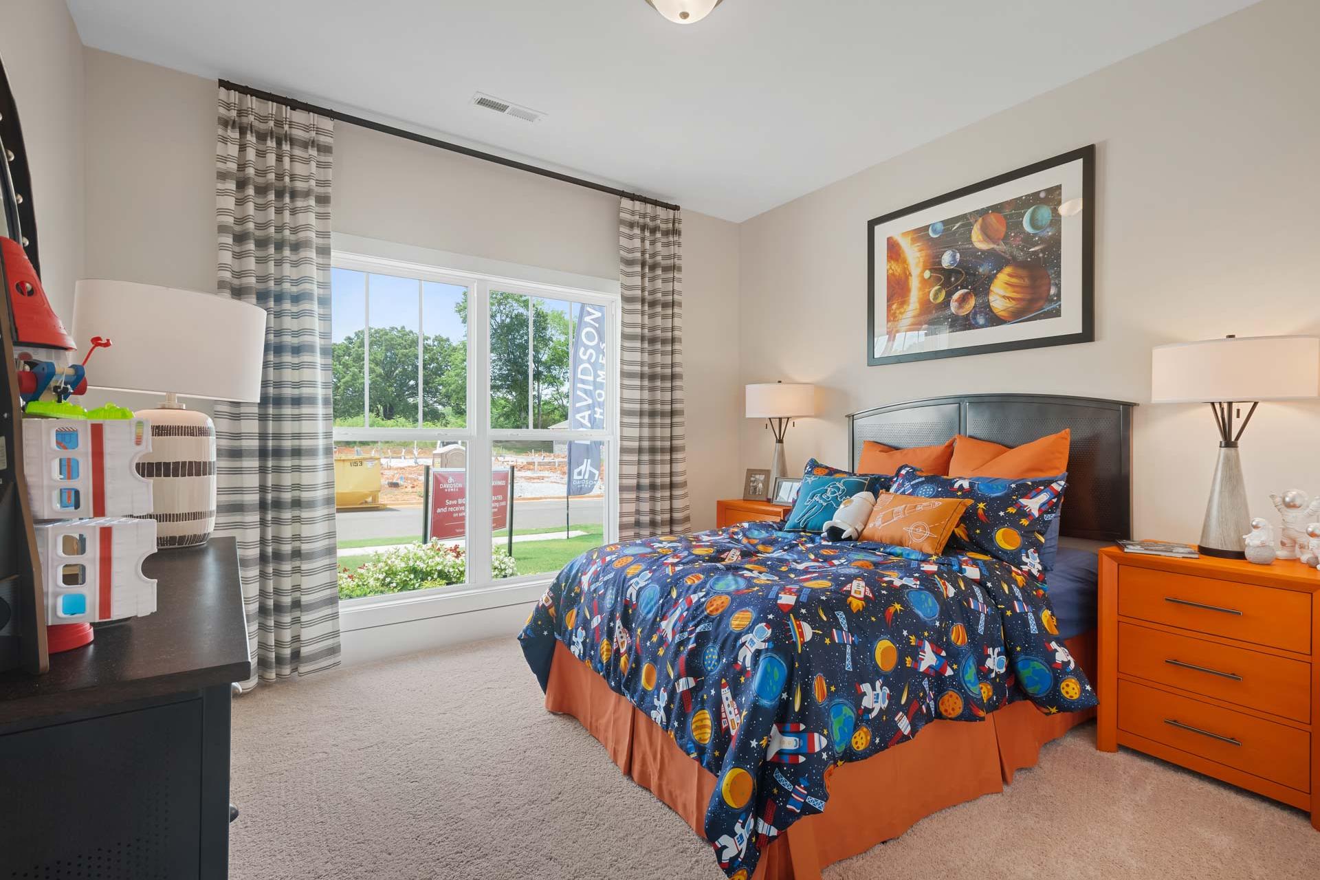 Space-themed child's bedroom at Flint Meadows in New Market Alabama with navy planet bedding, orange accents, and toys