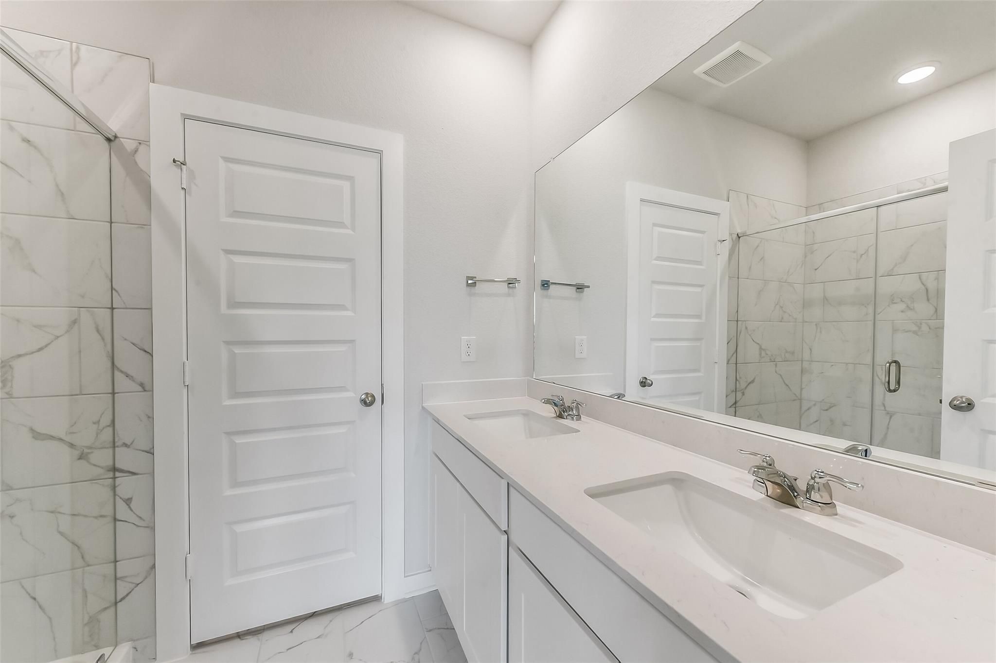Modern master bathroom double vanity with quartz countertop, marble tile shower, in Davidson Homes The Frio G, Magnolia TX