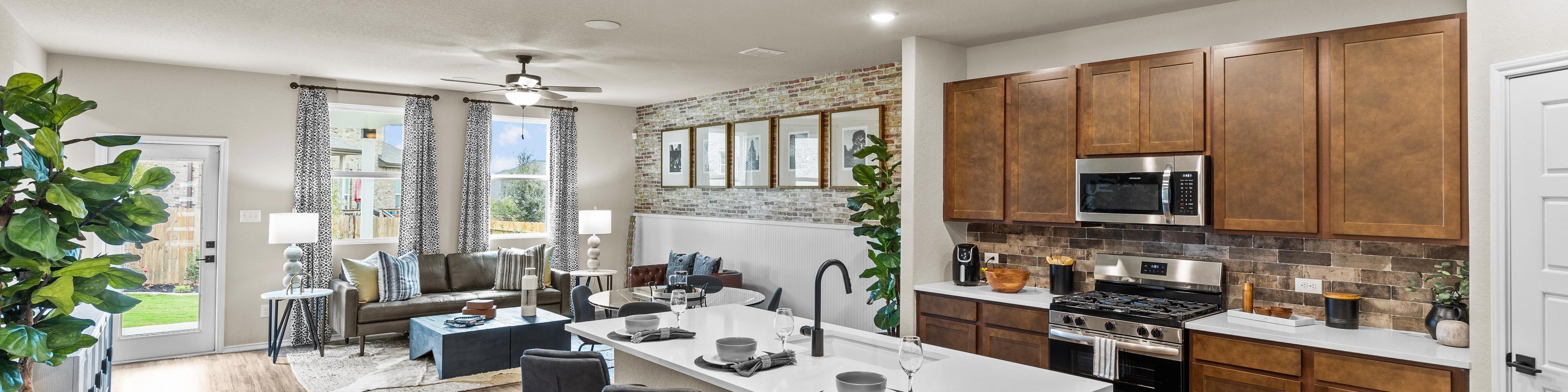 Spacious open-concept kitchen and living room at Bricewood in San Antonio TX with hardwood floors, white island, wood cabinets, and lounge seating