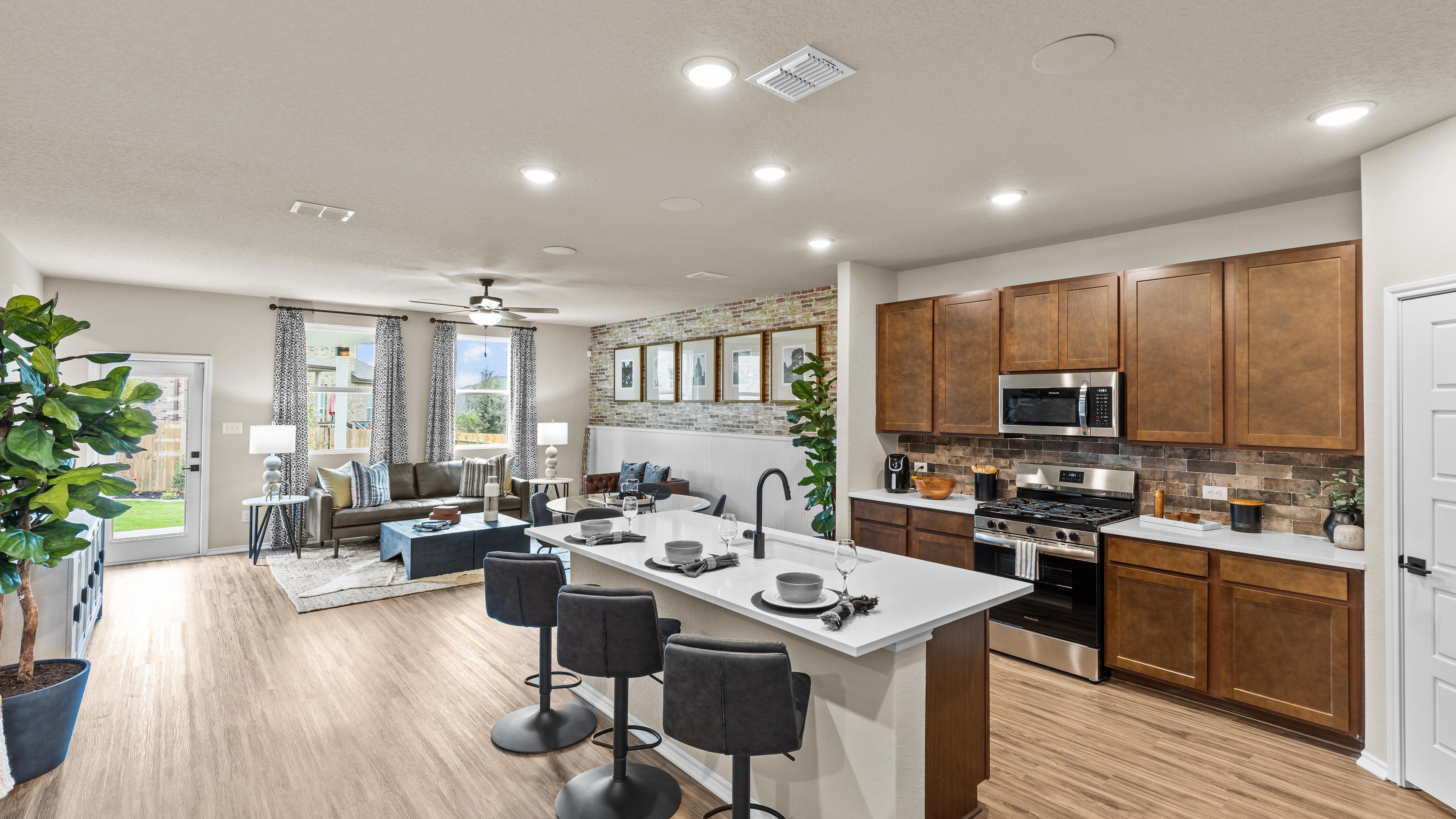 Spacious open-concept kitchen and living room at Bricewood in San Antonio TX with hardwood floors, white island, wood cabinets, and lounge seating