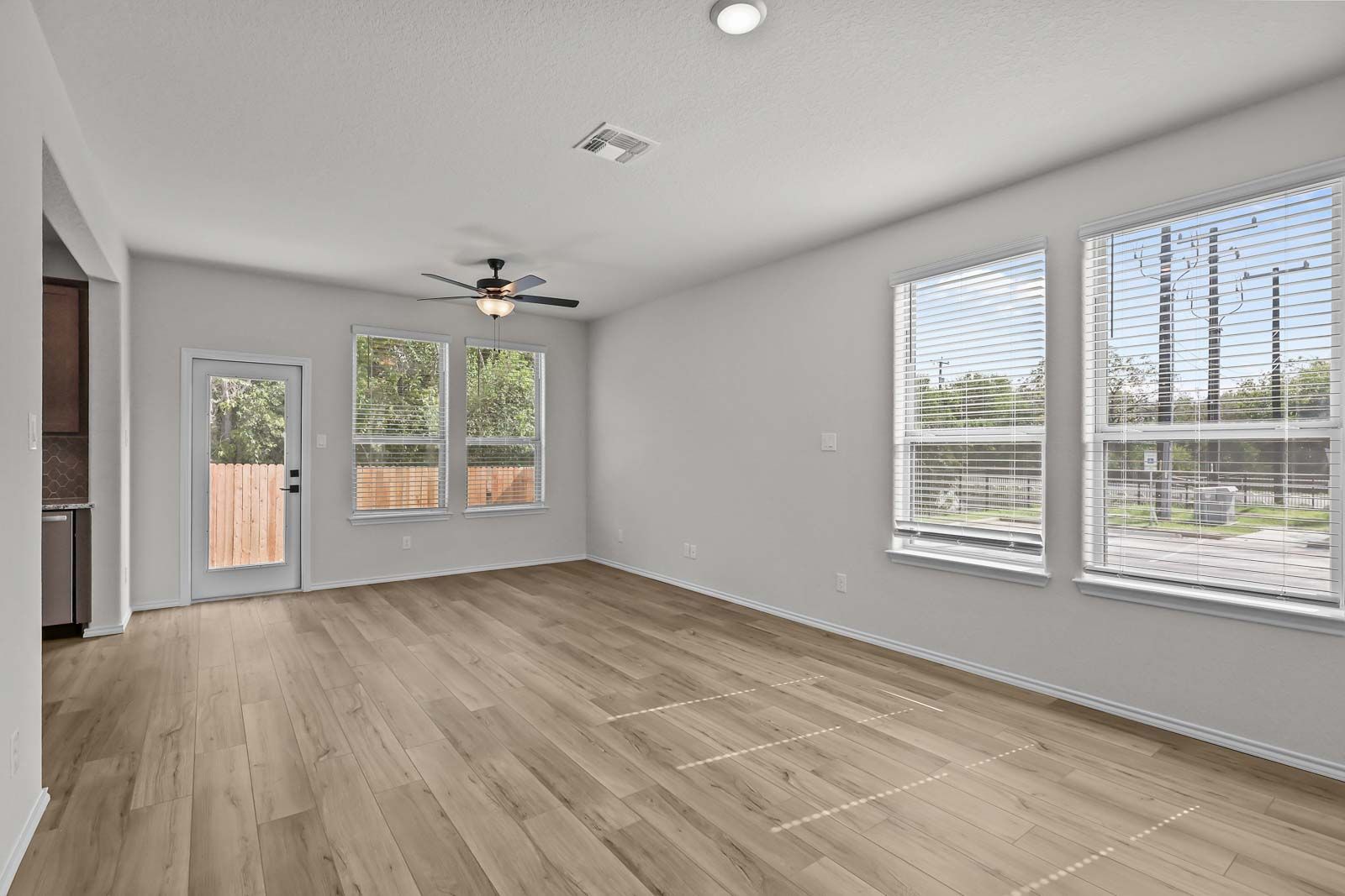 Spacious open-concept living area in The Florence B floor plan featuring wood-style flooring, ceiling fan, and natural light.