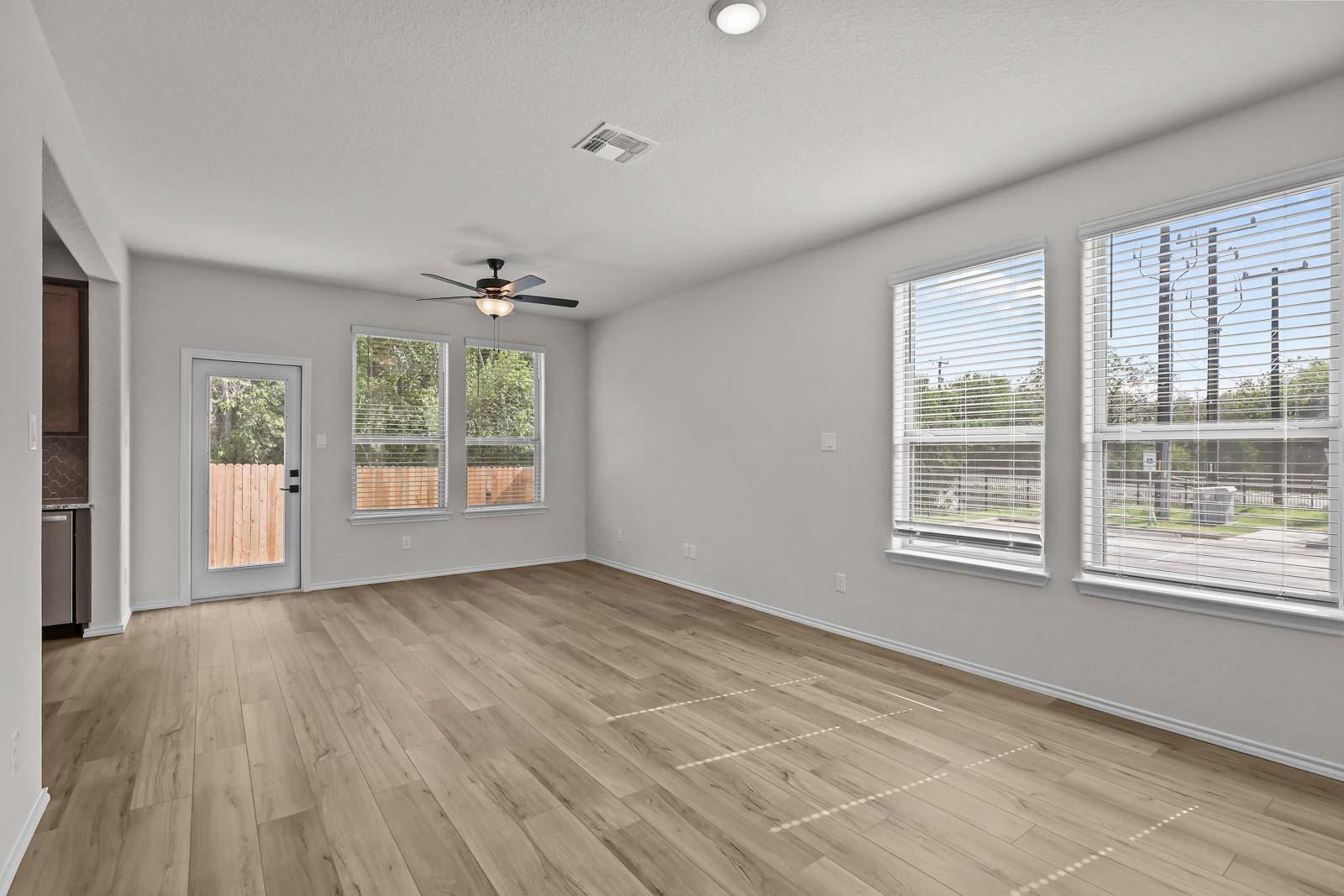 Spacious open-concept living area in The Florence B floor plan featuring wood-style flooring, ceiling fan, and natural light.