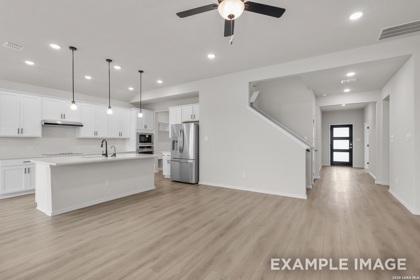 Open-concept kitchen with white cabinets and island in The Sequoia C floor plan by Davidson Homes in San Antonio, Texas.