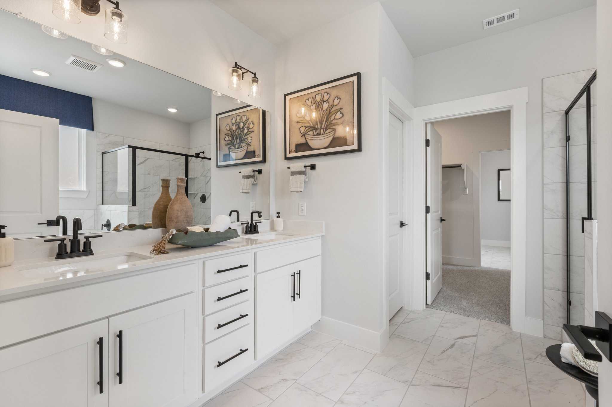 Modern primary bathroom at Mercer Meadows in Royse City Texas with double white vanity and glass shower