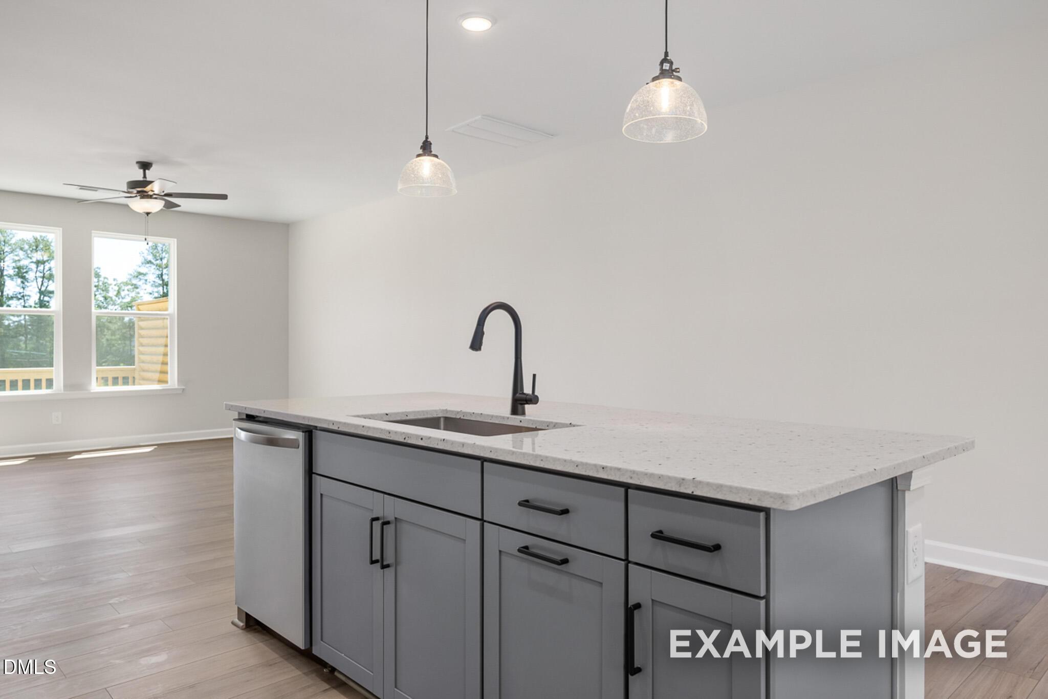Modern kitchen island with gray cabinetry and pendant lighting in The Mitchell floor plan at Camden Park, Knightdale, NC.