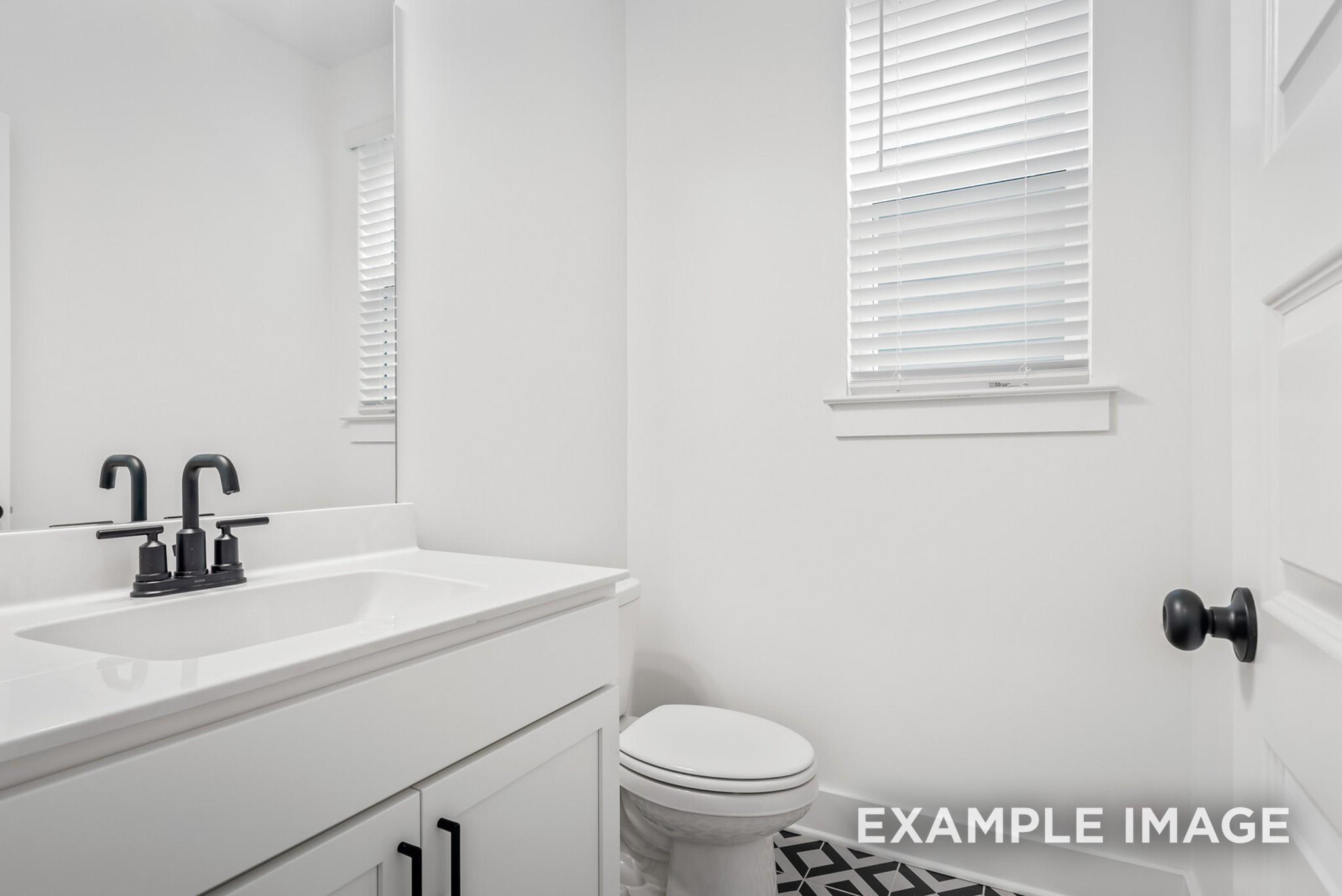 Modern guest bathroom with white vanity, black faucet, toilet, and patterned tile in Davidson Homes The Ridgeport C, Gallatin, TN