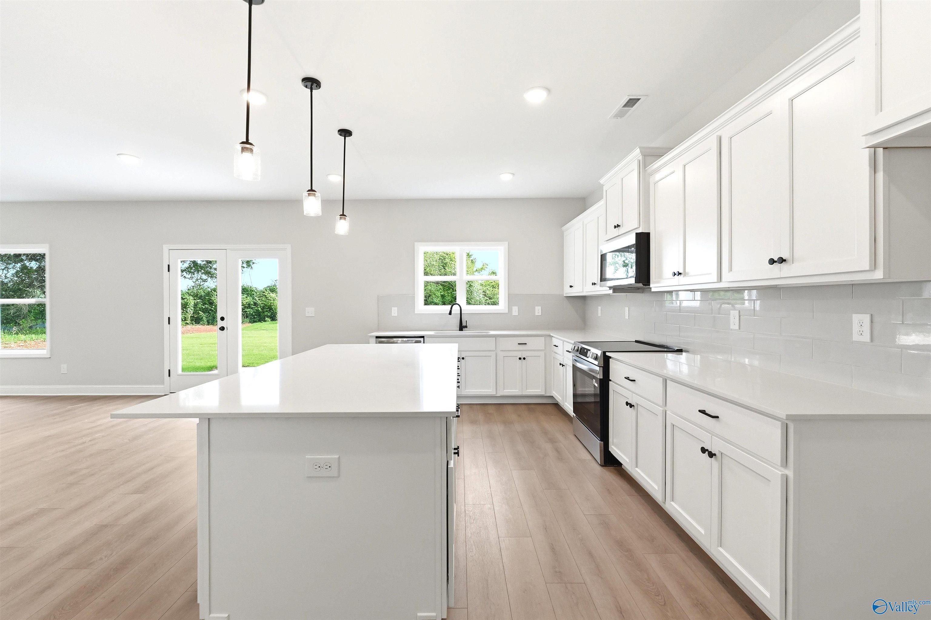 Modern white kitchen with quartz island and pendant lighting in The Chelsea D floor plan, Berry Cove, New Market, AL.