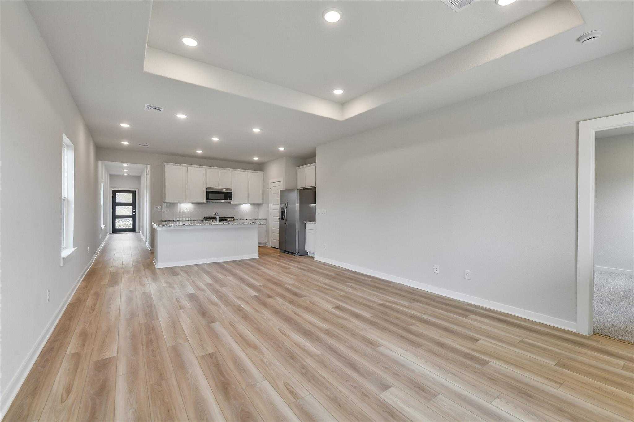 Spacious open kitchen with white cabinets, stainless appliances, and hardwood floors in Davidson Homes The Colorado G, Magnolia Texas