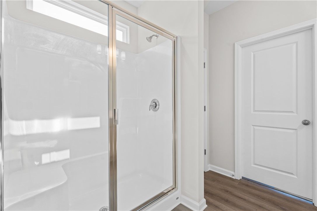 Elegant frameless glass shower with white subway tiles and chrome fixtures in The Luna B bathroom, Opelika, Alabama