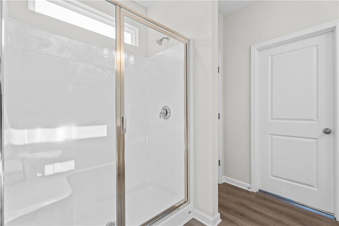 Elegant frameless glass shower with white subway tiles and chrome fixtures in The Luna B bathroom, Opelika, Alabama