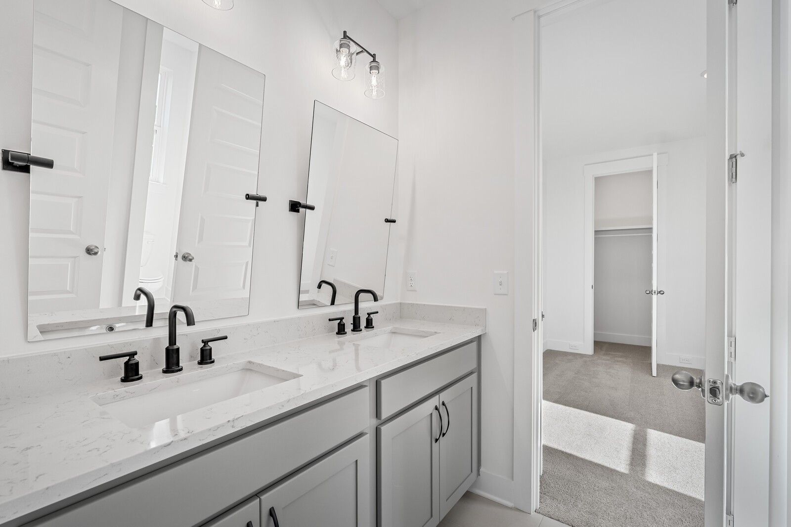 Modern double vanity with quartz counters, black faucets, and mirrors in The Alston A bathroom, Davidson Homes, Murfreesboro, TN