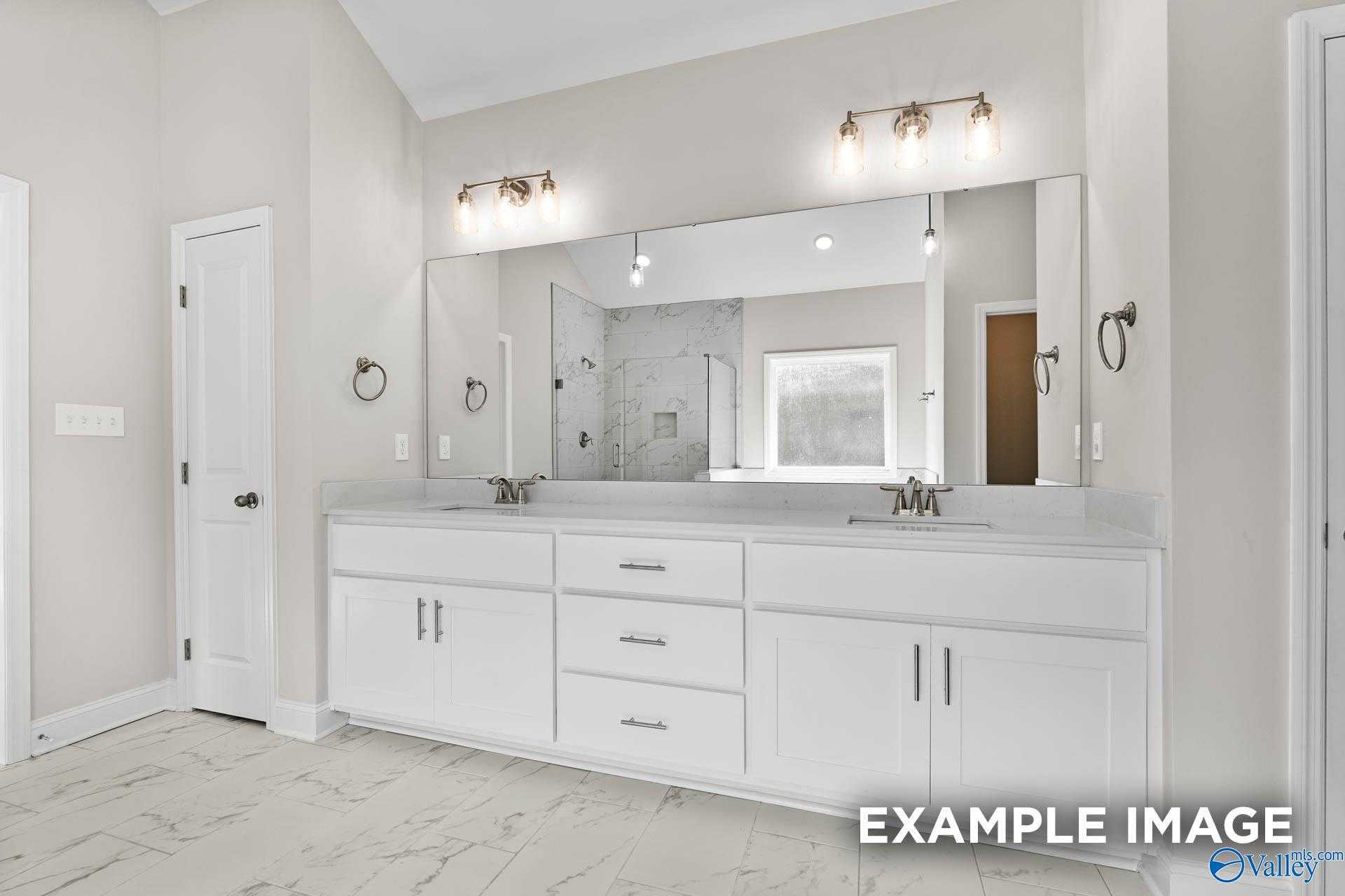 Elegant master bathroom double vanity with white shaker cabinets, large mirror, and tiled floor in Davidson Homes The Finleigh, Meridianville, Alabama