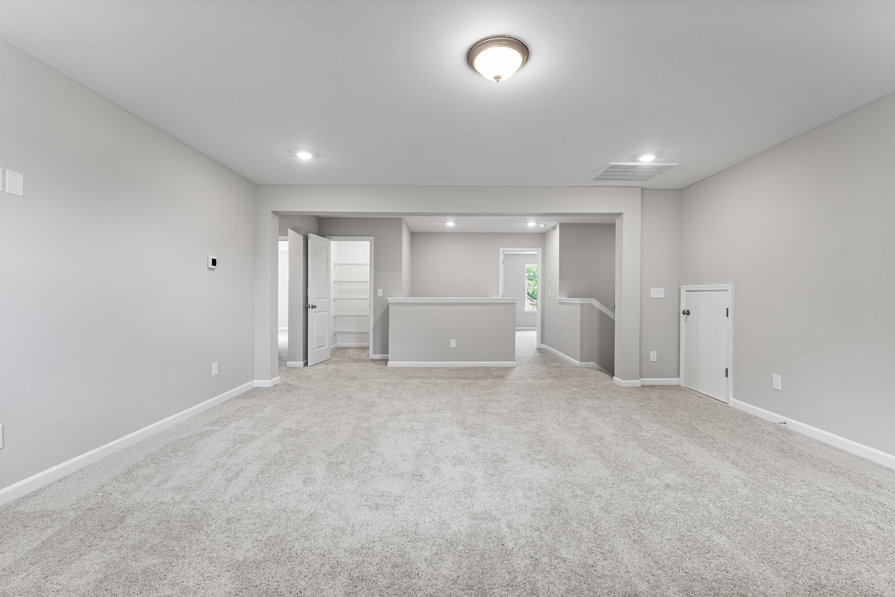 Spacious open foyer in The Avalon D home with gray walls, light carpet, recessed lighting, staircase, and doorways