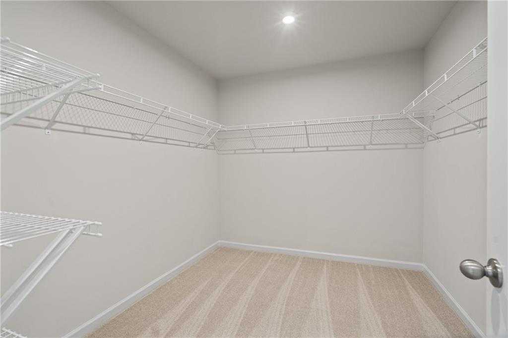 Spacious walk-in closet with wire shelving, hardwood floors, and neutral walls in Davidson Homes The Marion B, Kennesaw, Georgia