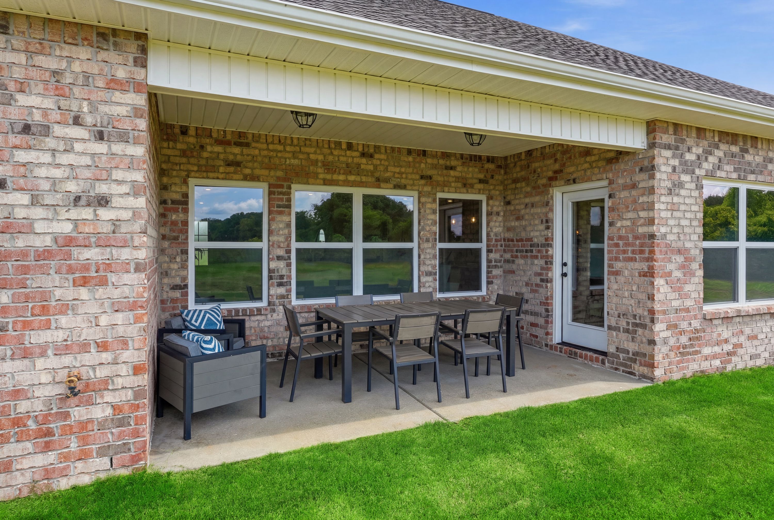 Covered brick patio with outdoor dining furniture at Riverton Preserve in Huntsville, Alabama by Davidson Homes.