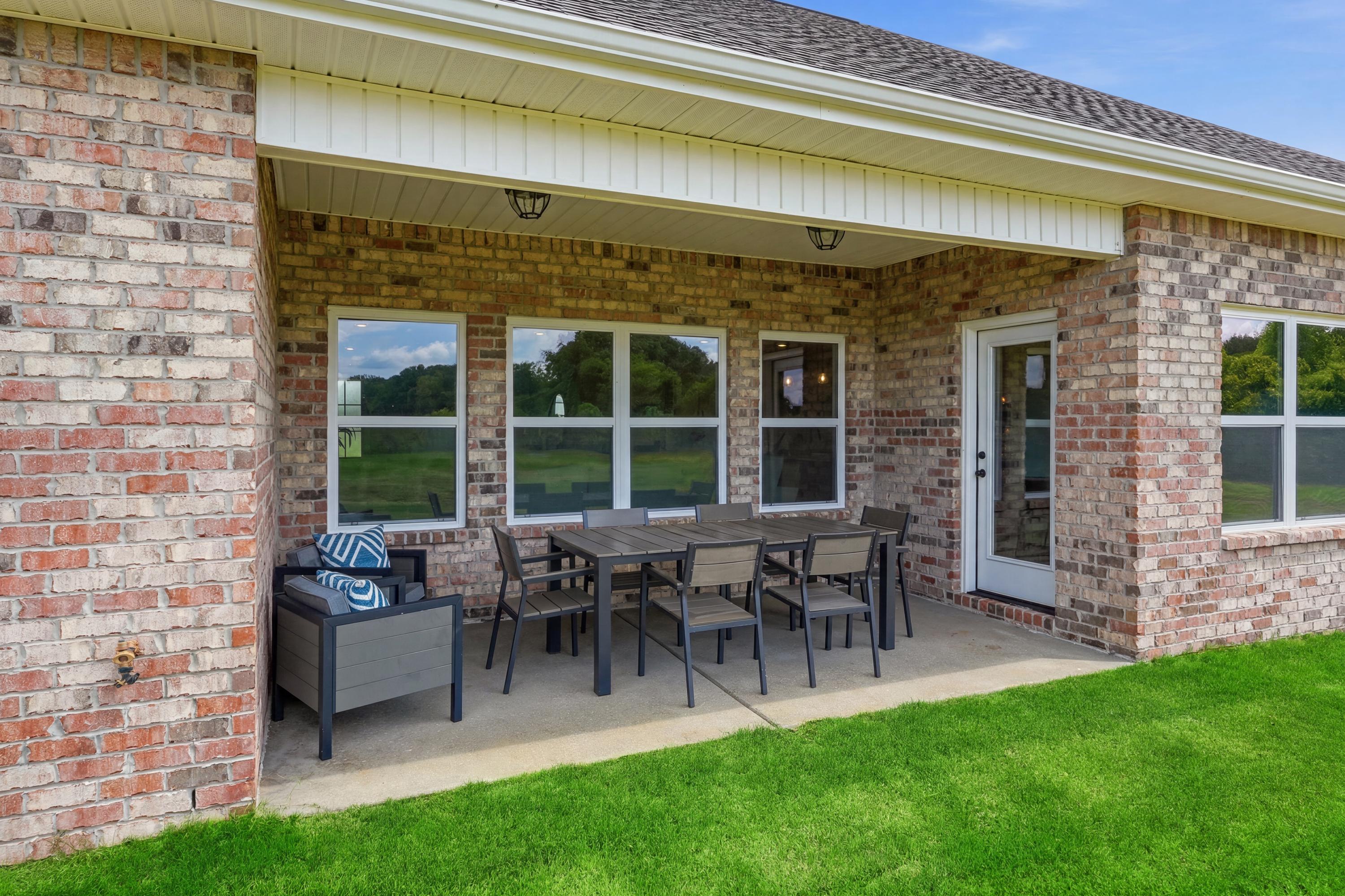 Covered brick patio with outdoor dining furniture at Riverton Preserve in Huntsville, Alabama by Davidson Homes.