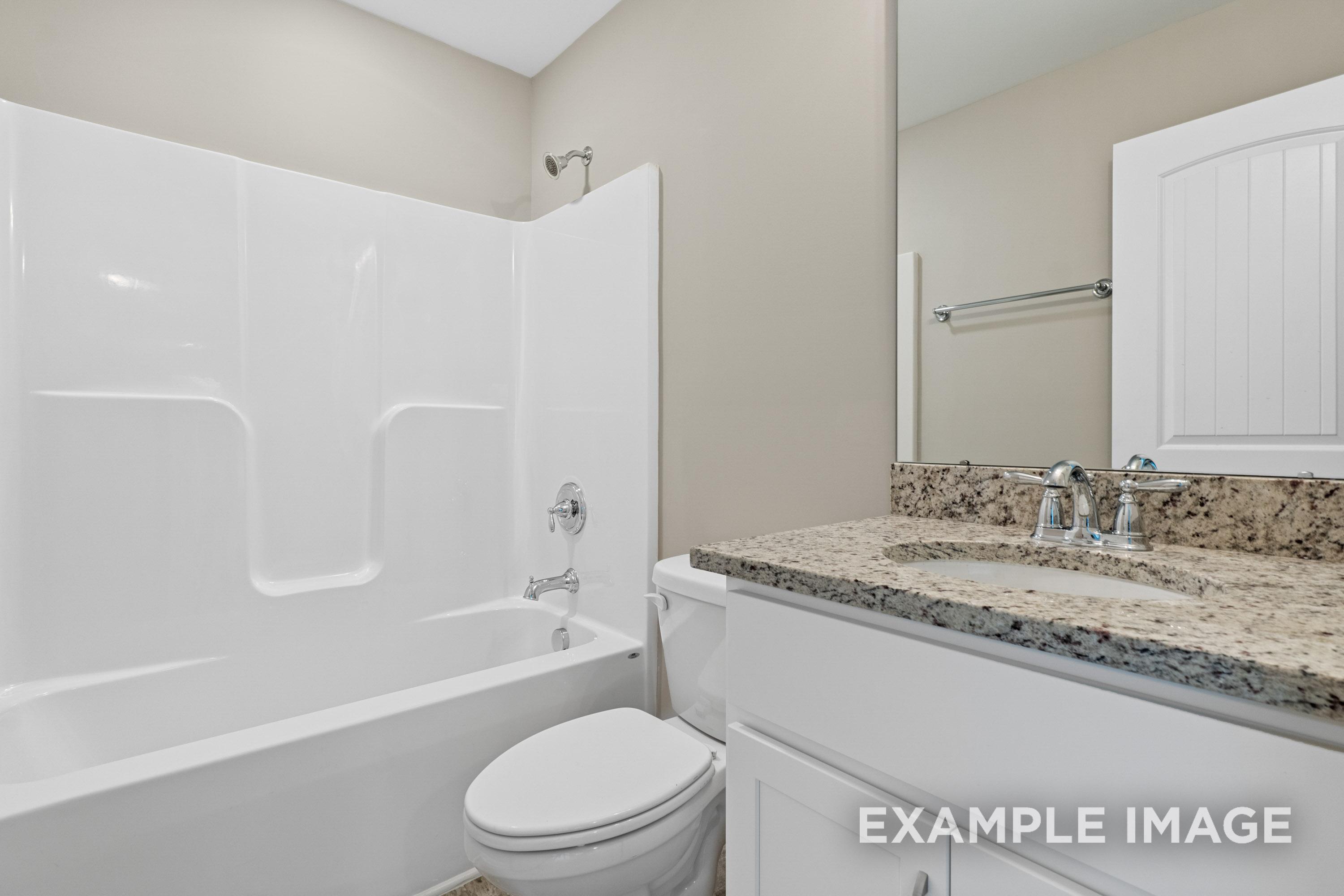 Modern master bathroom in The Madison B featuring white bathtub, walk-in shower, granite vanity, and large mirror