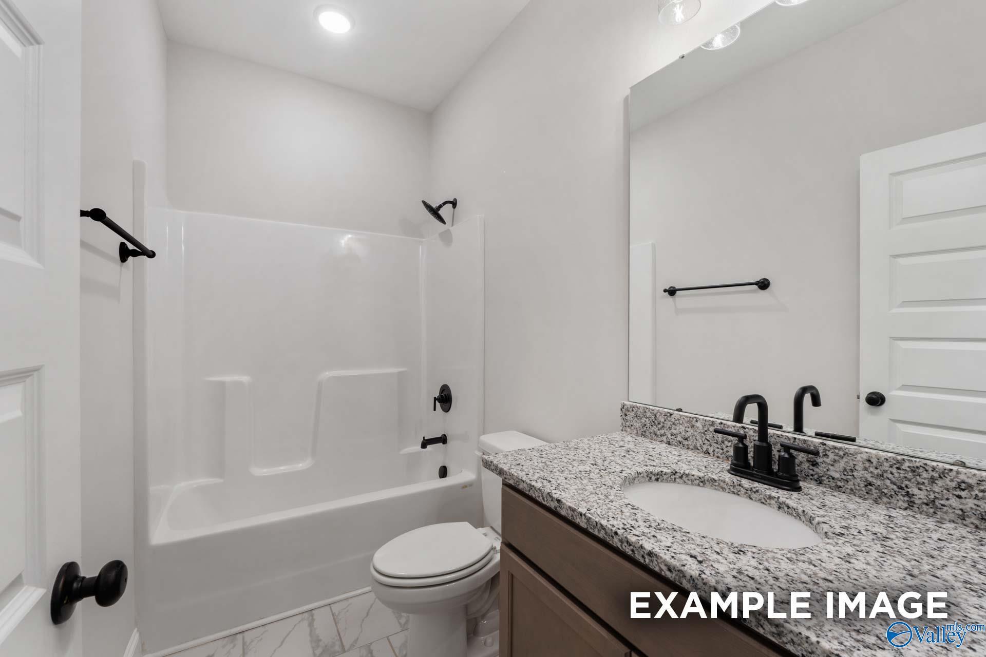 Modern guest bathroom featuring granite vanity, deep soaking tub, subway tile shower in Davidson Homes The Finleigh, Meridianville, Alabama