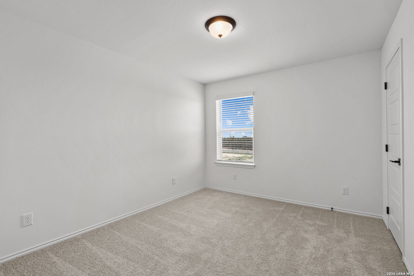Bright, carpeted bedroom with white walls and a single window in The Gillian C floor plan at Meadows at Oak Creek, TX.
