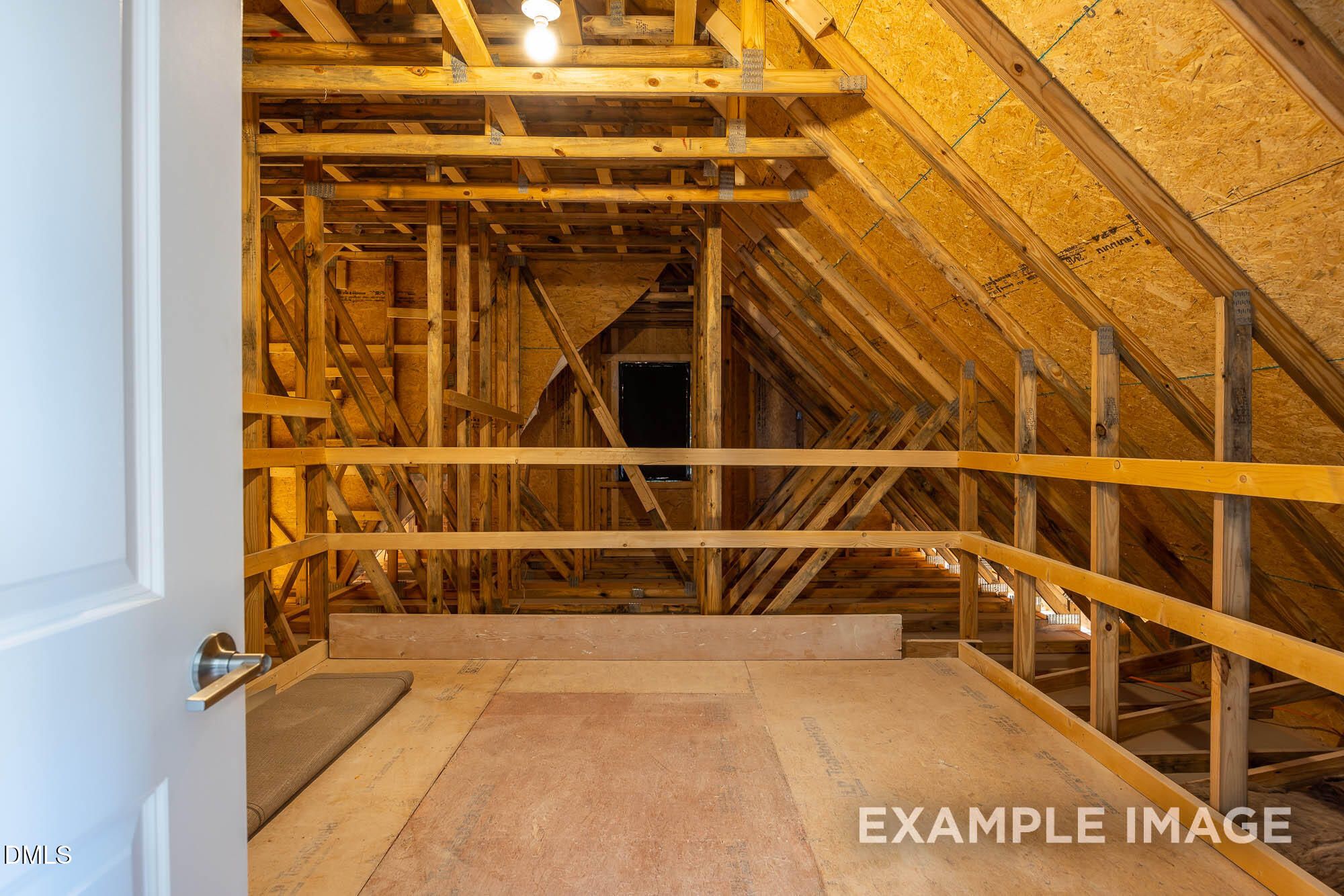 Unfinished bonus room with wooden framing, yellow insulation, and plywood flooring in Davidson Homes The Cypress B II, Angier, NC