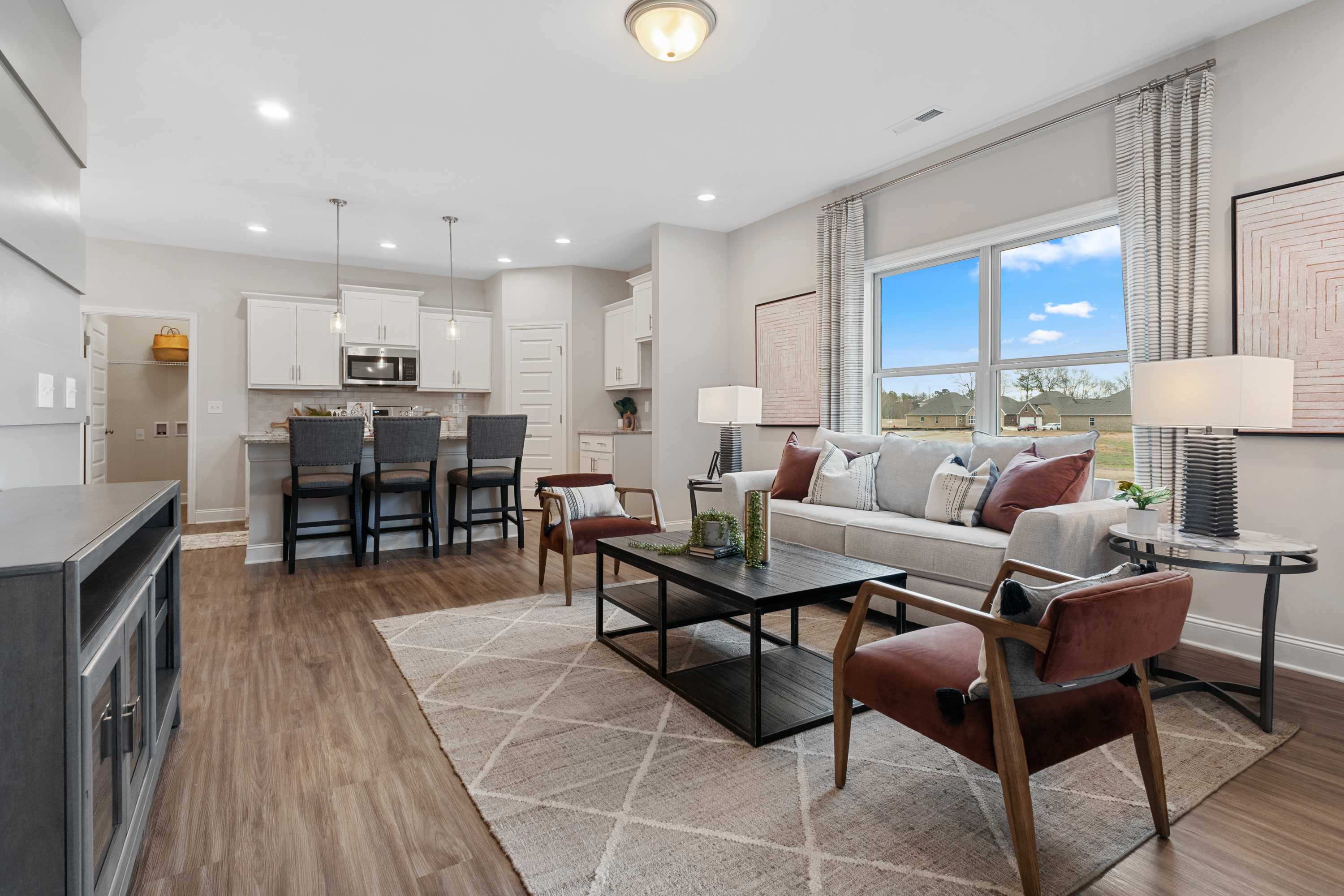 Open-concept kitchen and living room at The Retreat at Cain Park in Hartselle AL with hardwood floors, white cabinetry, and beige sofa
