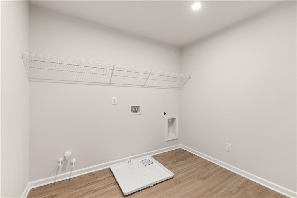 Modern laundry room with wire shelving, washer-dryer hookups, and hardwood floors in Davidson Homes The Marion B, Kennesaw, GA