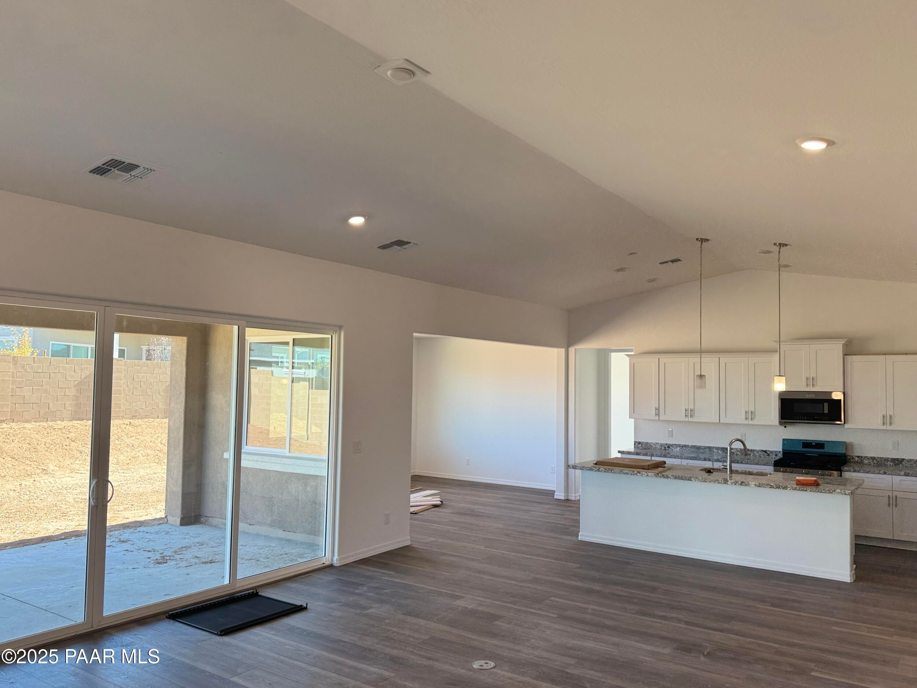 Open-concept kitchen with white island, stainless appliances, and sliding doors to patio in Davidson Homes The Sunrise II A, Prescott, Arizona
