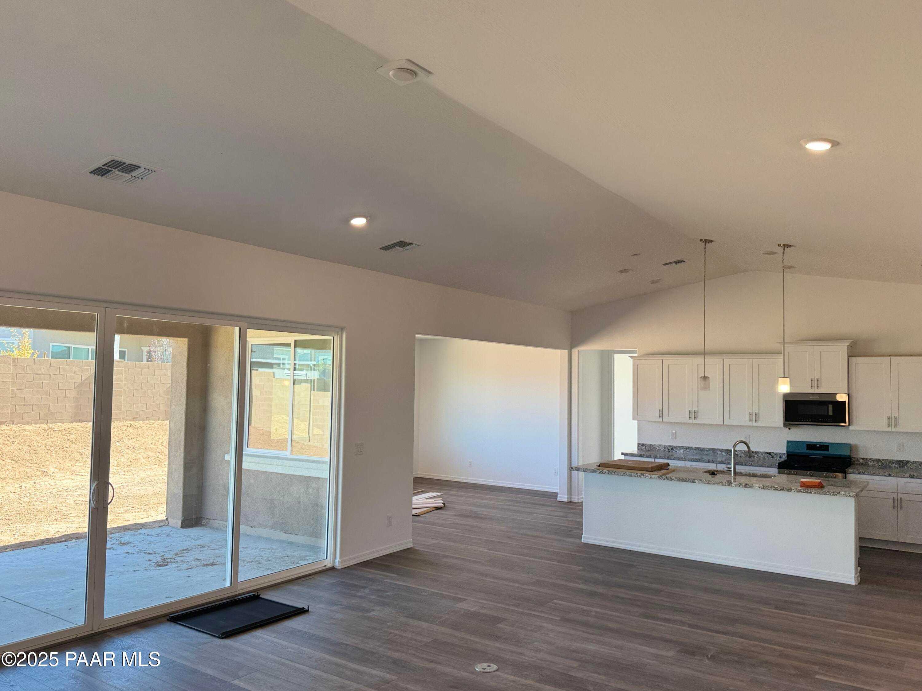 Open-concept kitchen with white island, stainless appliances, and sliding doors to patio in Davidson Homes The Sunrise II A, Prescott, Arizona