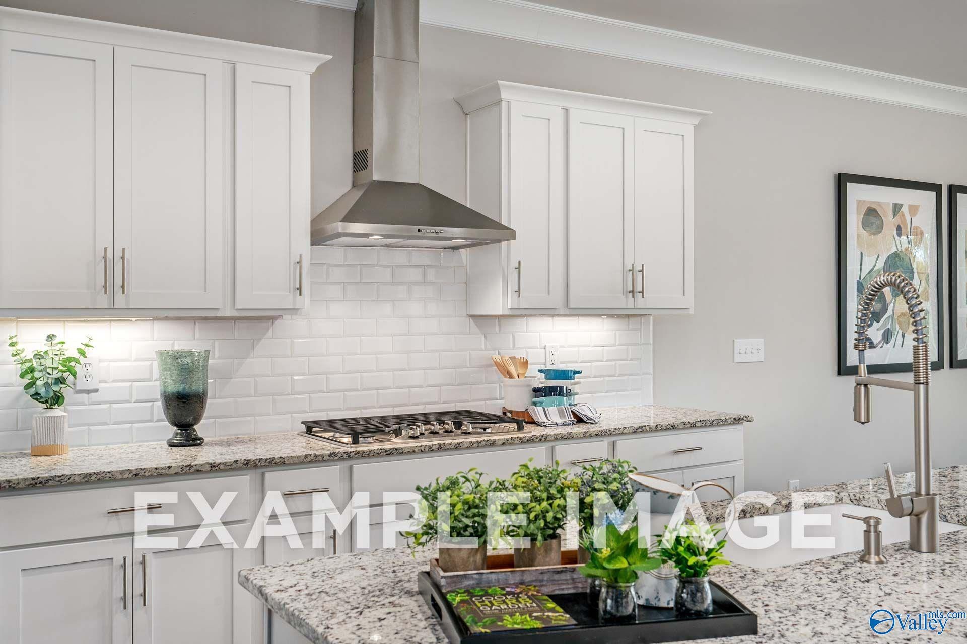 Modern kitchen with white shaker cabinets, subway tile backsplash, granite counters, and gas cooktop in The Harrison floor plan, Hartselle