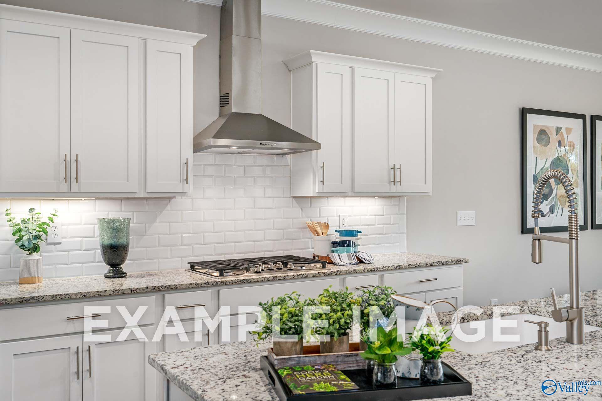 Modern kitchen with white shaker cabinets, subway tile backsplash, granite counters, and gas cooktop in The Harrison floor plan, Hartselle
