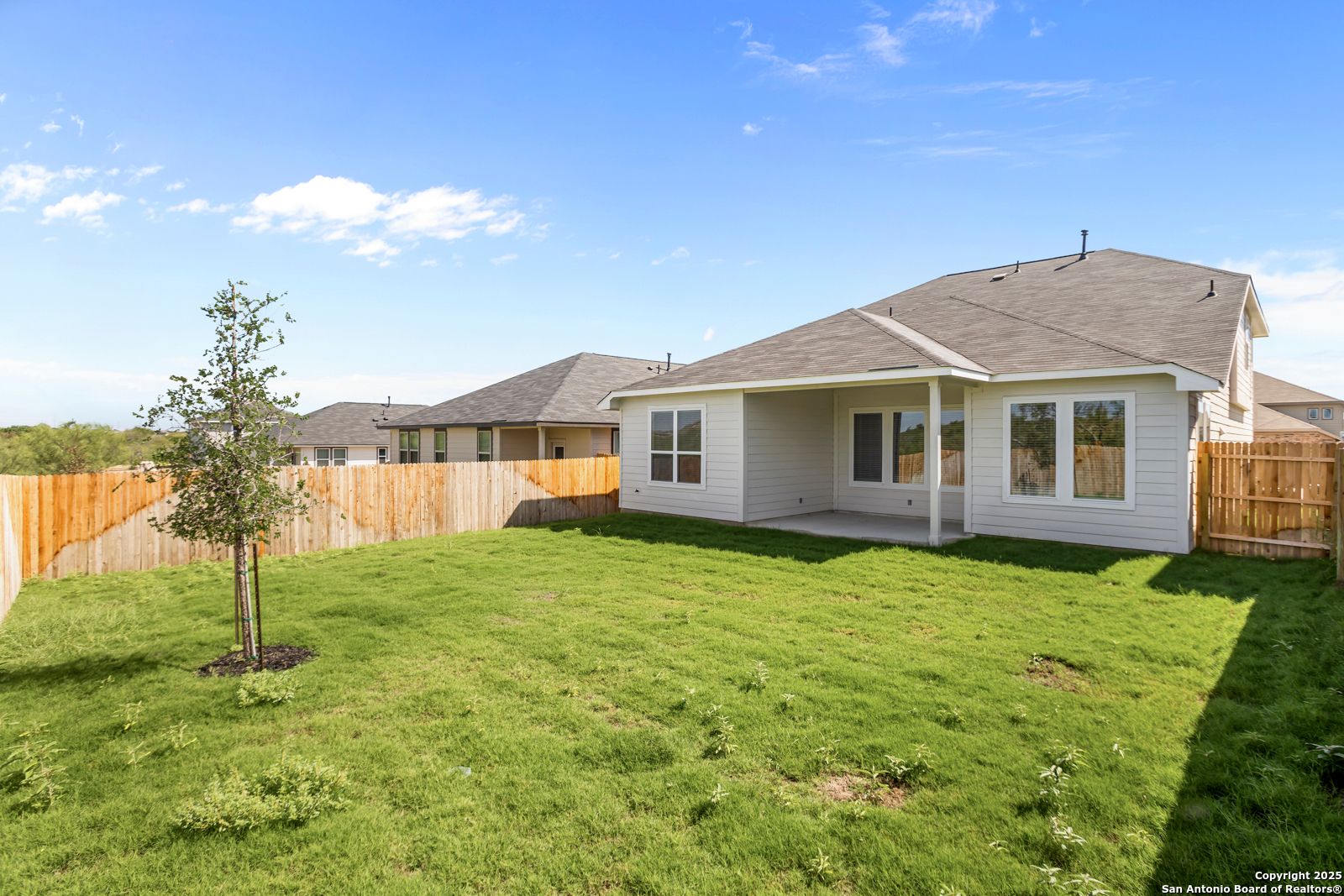 Covered back patio and spacious fenced backyard with lush grass in Davidson Homes The Sequoia A, Horizon Pointe, Converse, Texas
