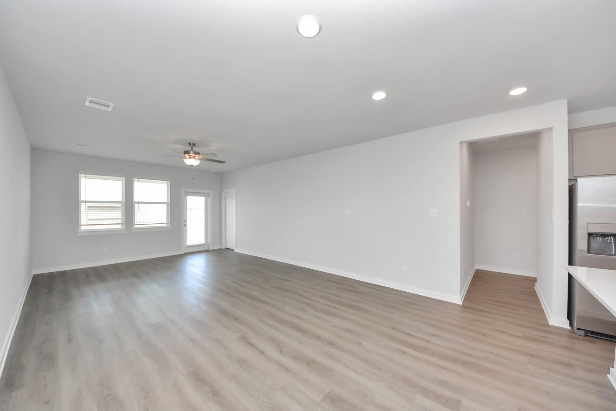 Bright open-concept living room with luxury vinyl plank flooring in Davidson Homes' San Marcos E plan, Emberly, Beasley, TX