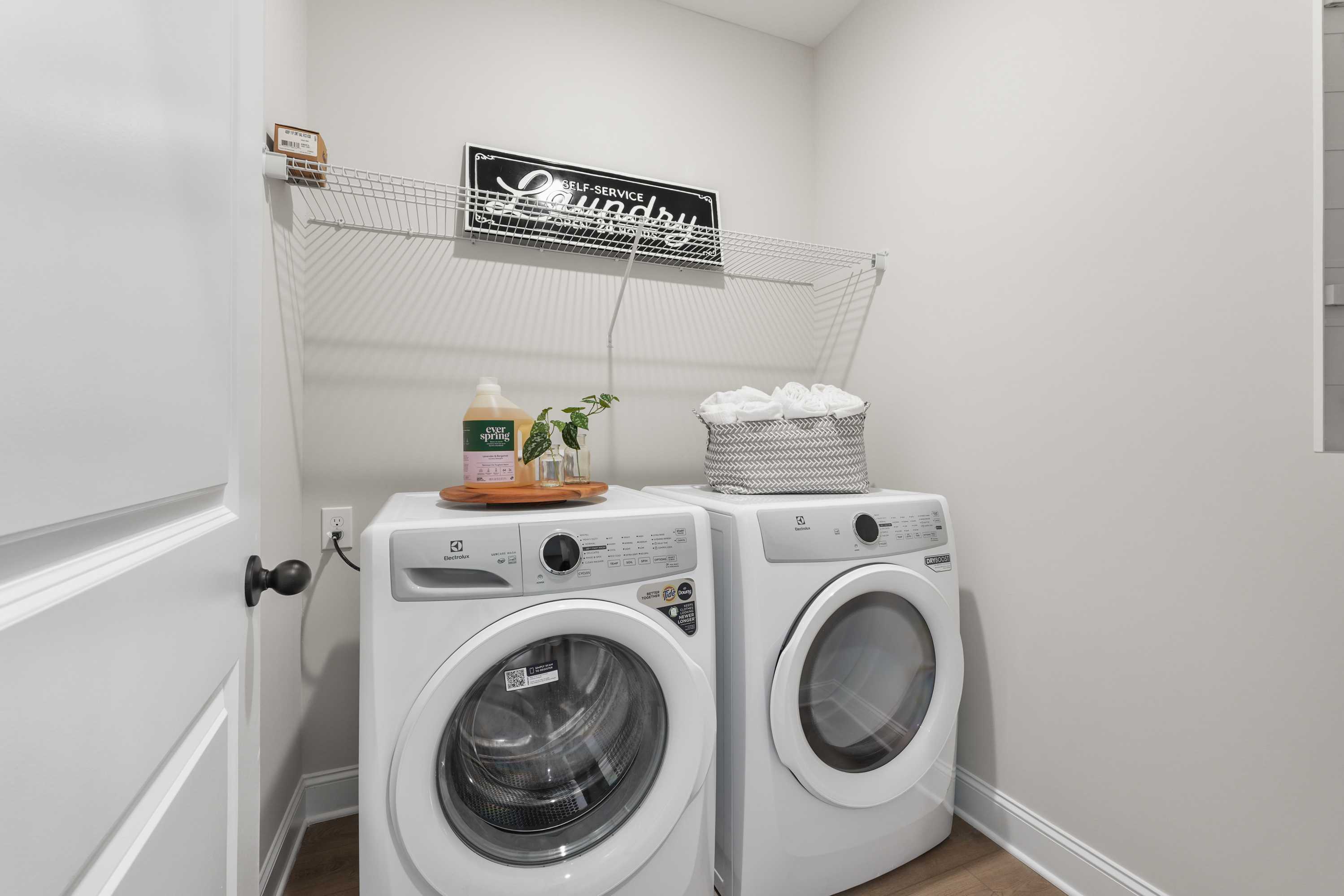 Spacious laundry room in Ramsay Cove, Owens Cross Roads AL with side-by-side white washer dryer, storage shelves and organized detergents