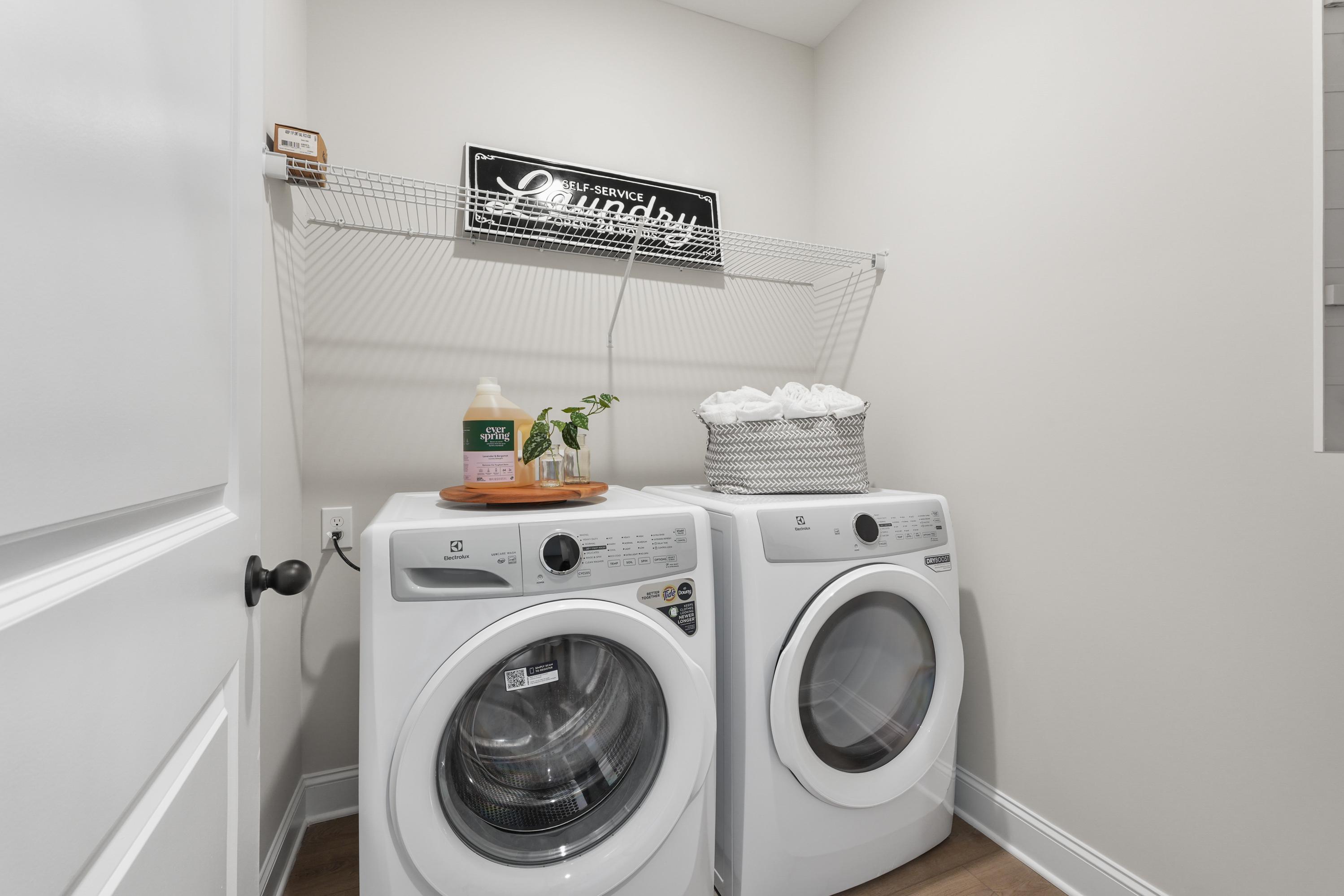 Spacious laundry room in Ramsay Cove, Owens Cross Roads AL with side-by-side white washer dryer, storage shelves and organized detergents