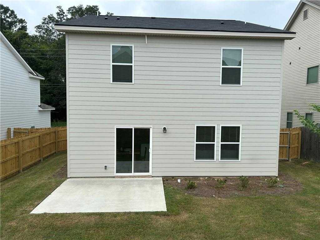 Rear view of Davidson Homes The Bartlett two-story with sliding glass doors, concrete patio, and fenced backyard in Summer Vineyard, Phenix City, Alabama