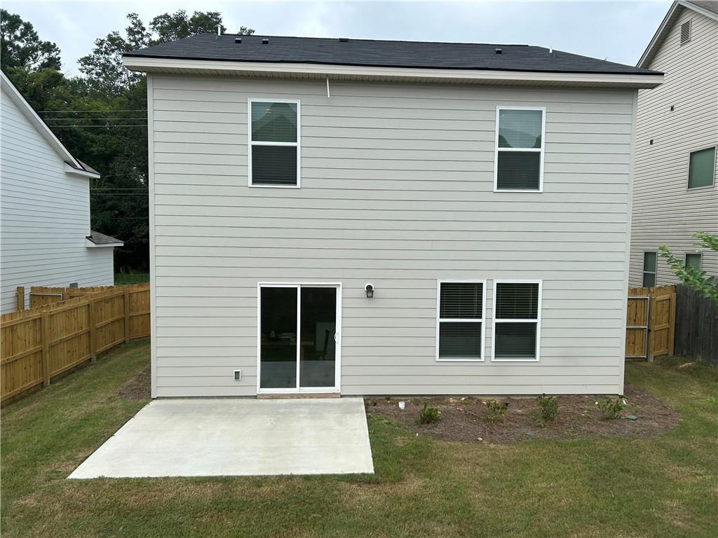 Rear view of Davidson Homes The Bartlett two-story with sliding glass doors, concrete patio, and fenced backyard in Summer Vineyard, Phenix City, Alabama