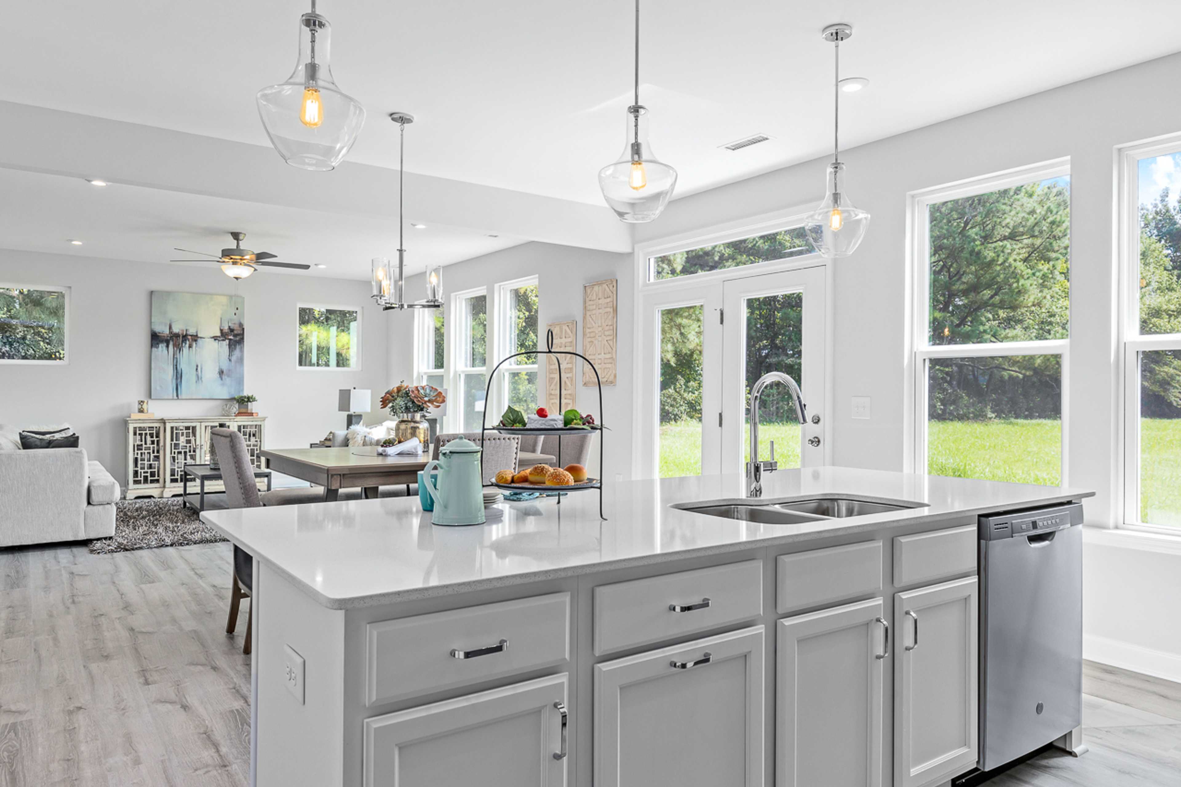 Spacious open-concept kitchen at Stagecoach Corner in Mebane NC with white island, stainless sink, pendant lights, hardwood floors