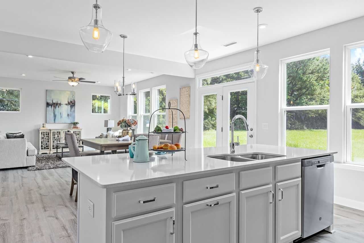 Spacious open-concept kitchen at Stagecoach Corner in Mebane NC with white island, stainless sink, pendant lights, hardwood floors