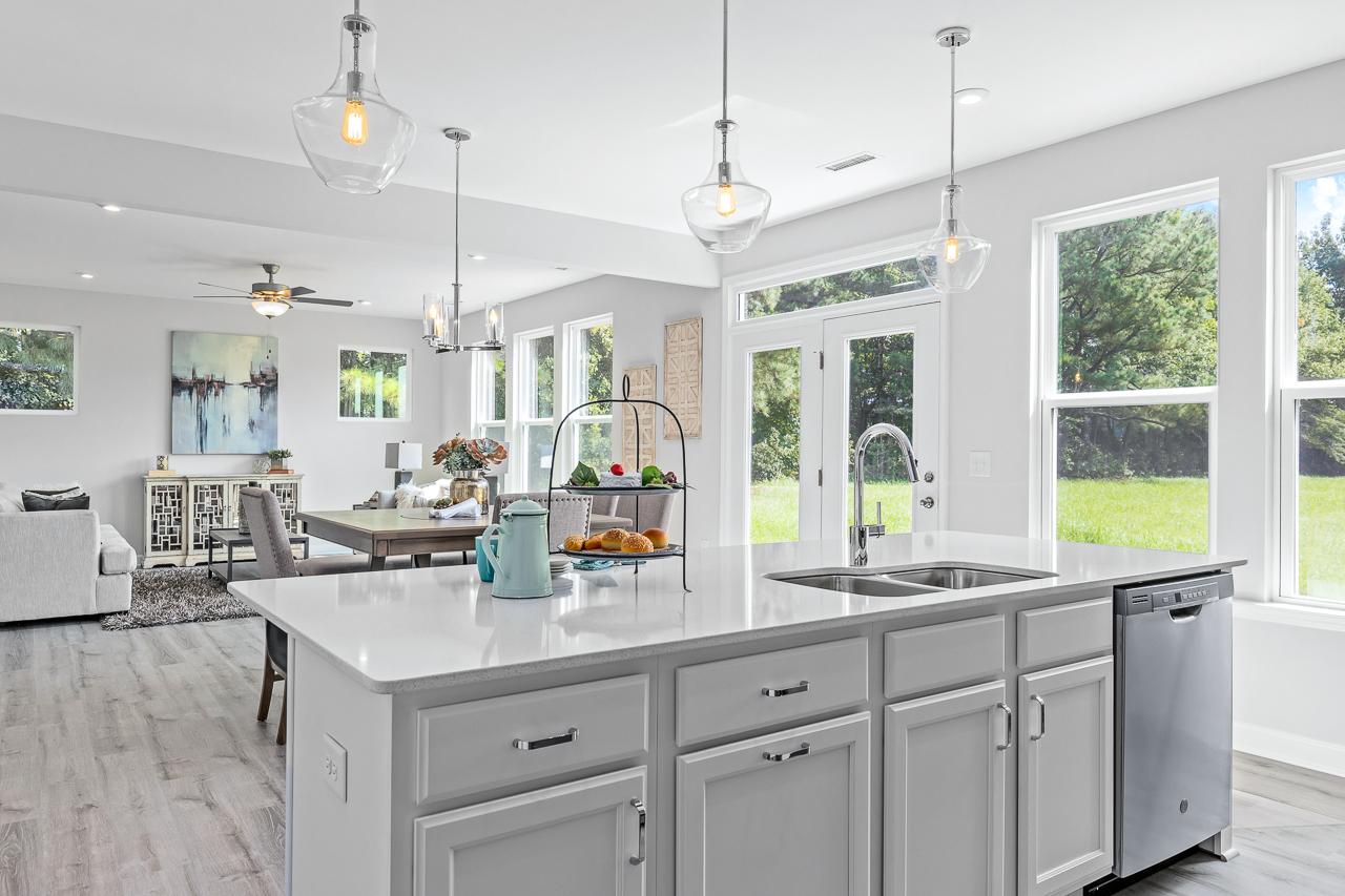 Spacious open-concept kitchen at Stagecoach Corner in Mebane NC with white island, stainless sink, pendant lights, hardwood floors